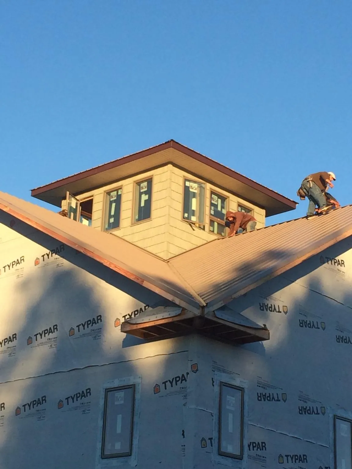 Roofers working around a rooftop cupola on a new metal roof at sunset — Roof Waterproofing in Norris by Roofing Brothers